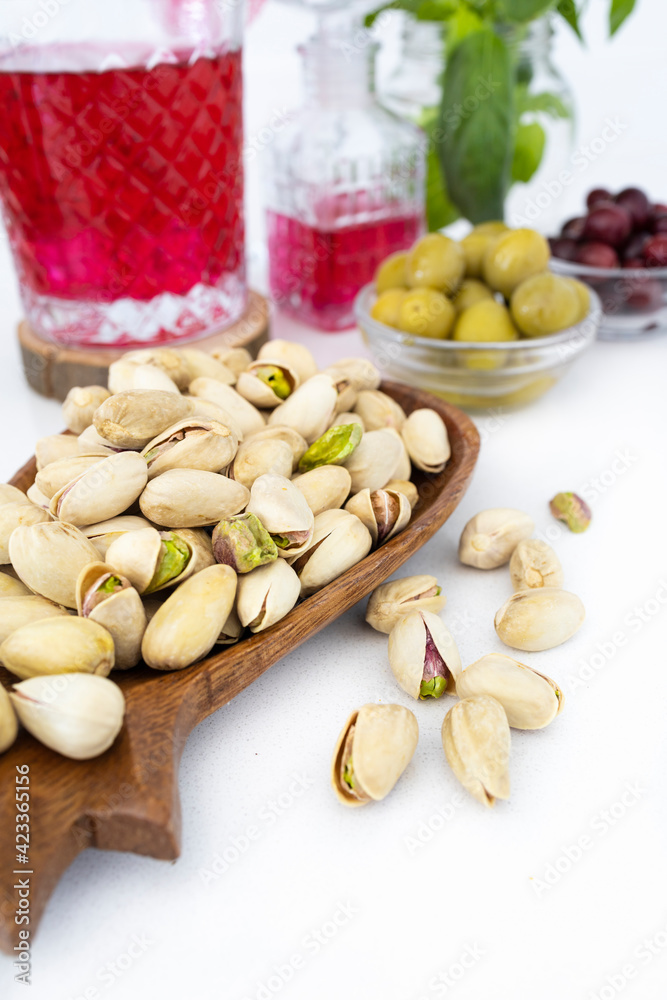 Appetizer time. Coconut wood tray with pistachios. Nuts and olives, healthy snacks. Mediterranean diet. Food photography
