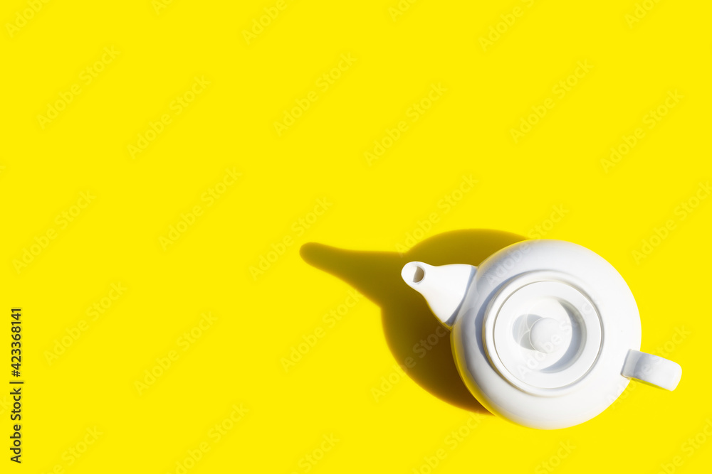 White ceramic teapot on yellow background.