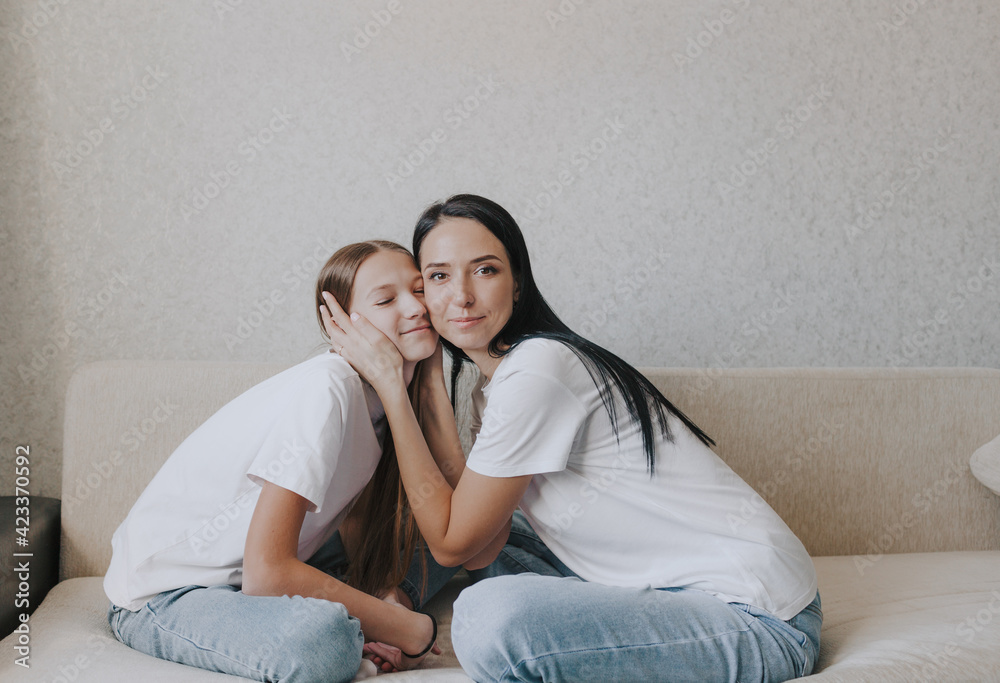 mom and daughter are sitting on the couch hugging, a large portrait. mom and daughter are sitting on the couch hugging, a large portrait.