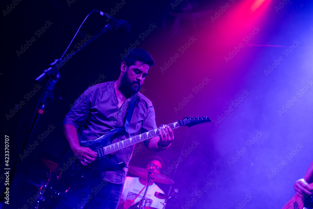 © Damián Basante - Musician playing electric guitar during rock band live concert. Black hair male guitar player performing on stage. Music foggy lights show © Damián Basante - Musician playing electric guitar during rock band live concert. Black hair male guitar player performing on stage. Music foggy lights show