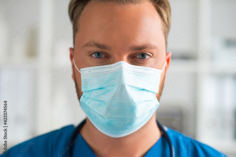 Professional medical doctor in hospital office, Portrait of young and confident physician in protective mask. Professional medical doctor in hospital office, Portrait of young and confident physician in protective mask.