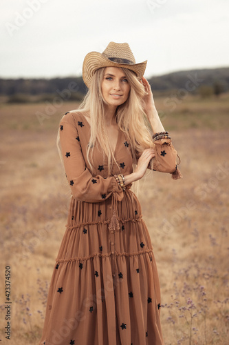 Girl in a bohemian style in the steppe. Blonde girl with a hat on the prairie.