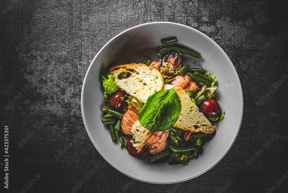 Green Bean Salad with Boiled Eggs, Salmon, Tomatoes and Arugula in a bowl on Dark grey black slate background Green Bean Salad with Boiled Eggs, Salmon, Tomatoes and Arugula in a bowl on Dark grey black slate background