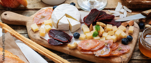 Cheese and cold cuts on a board with a variety of snacks and fingerfoods, fruits and nuts. Banner. photo