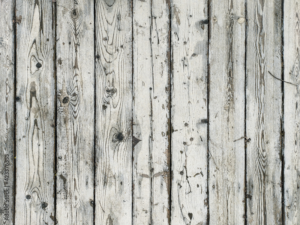 Obraz premium Old white wood plank texture, arranged vertically, light natural background. The texture of the wood is visible through the cracked and worn layer of white paint.