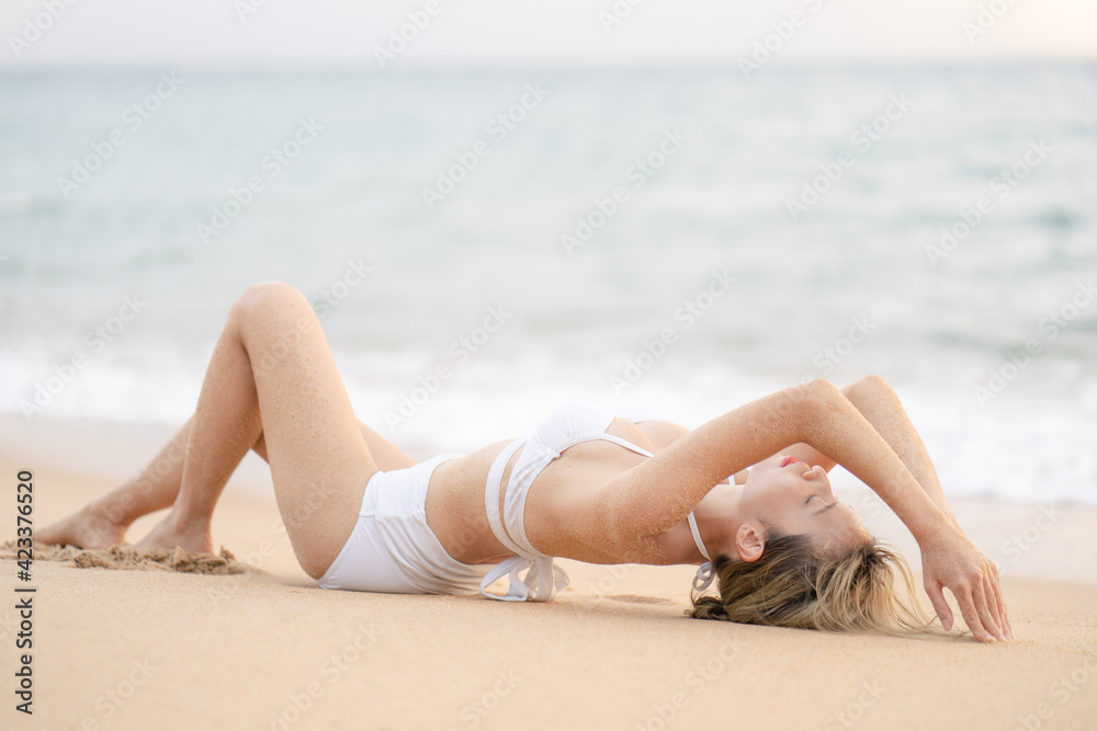 Woman in bikini lying down on sand beach relaxing sunbathing. Woman in bikini lying down on sand beach relaxing sunbathing.