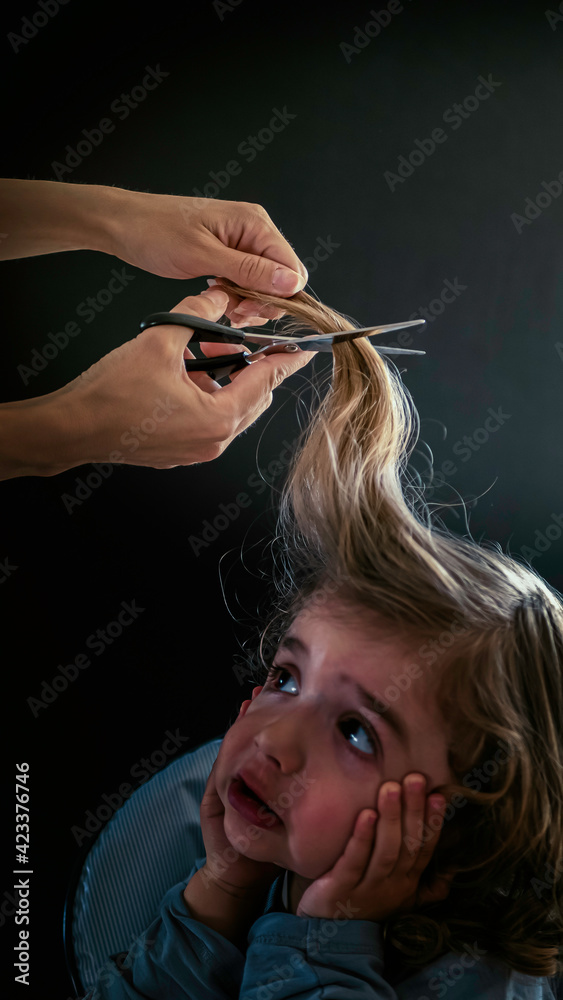 Obraz premium Little boy, toddler is afraid and doesn't want to cut his hair. A baby boy is fearful of getting his haircut for the first time.