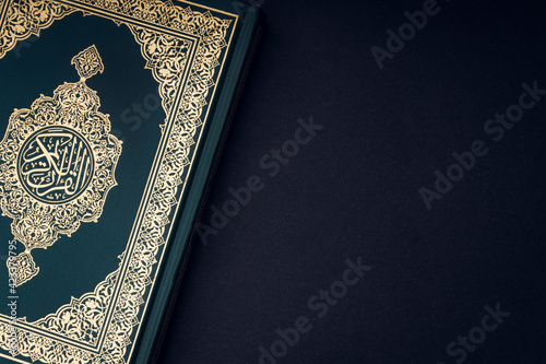 Holy Al Quran with written arabic calligraphy meaning of Al Quran on black background. Copy space and crop fragment