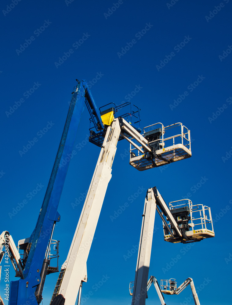 Articulated boom lift. Aerial platform lift. Telescopic boom lift against blue sky. Mobile construction crane for rent and sale. Maintenance and repair hydraulic boom lift service. Cherry pickers.