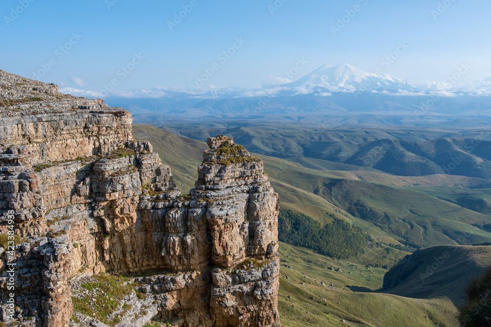 View of Bermamyt plateau rocks and mount Elbrus on sunny day. Karachay-Cherkessia, Caucasus, Russia.