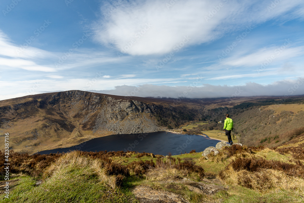 young man cyclist standing on rock with lough tay lake in the background