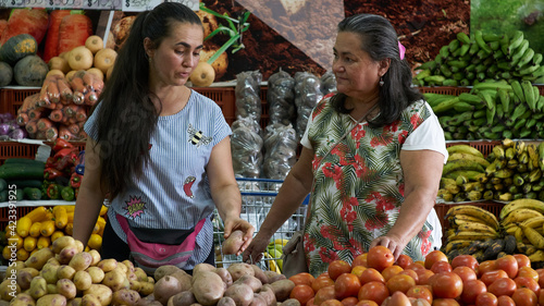 Latin American ladies buying organic fruits and vegetables in the supermarket