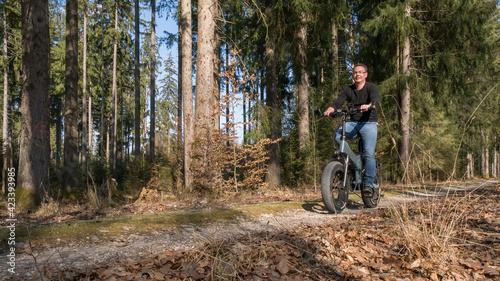 Young man rides big electric bike through the forest