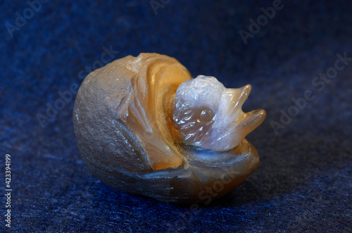 Toy cheeper in the nest, a souvenir, made of semiprecious stone on a blue background