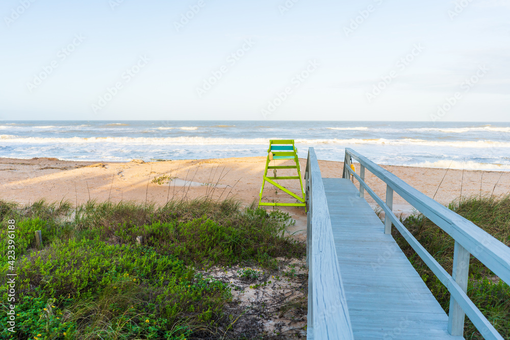 Boardwalk leading to sandy beach with a lifeguard chair
