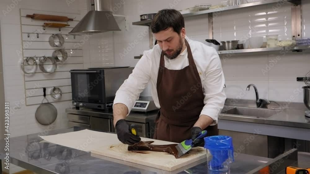 A male pastry chef tempering chocolate in a professional pastry kitchen. A male pastry chef tempering chocolate in a professional pastry kitchen.