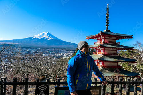 Photography A man admiring Chureito Pagoda and view on Mt Fuji, Japan, captured on a clear, sunny day in winter