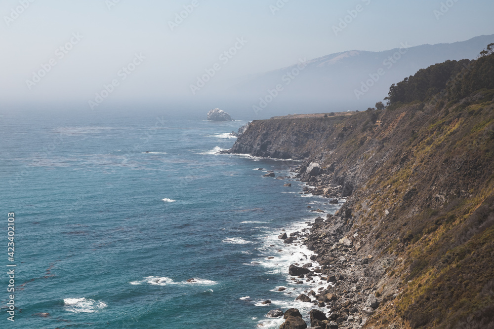 Beautiful foggy coastline with cliffs and distant mountains in Big Sur, California