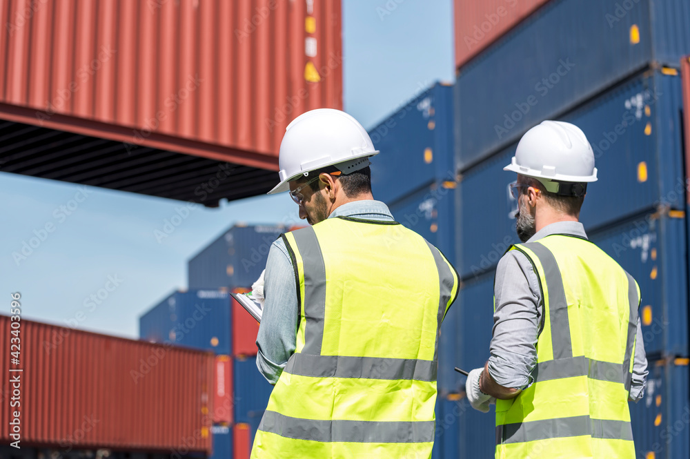 Logistics engineer and inspector working togetter and discussing in shipping containerin commercial transport port Logistics engineer and inspector working togetter and discussing in shipping containerin commercial transport port