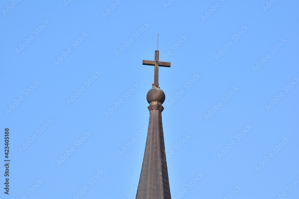 Church Roof with a cross. Church building roof with holy cross. Cloudy moody blue sky background. Minimal architecture design and detail. Exterior design and detail. Abstract architecture. Church Roof with a cross. Church building roof with holy cross. Cloudy moody blue sky background. Minimal architecture design and detail. Exterior design and detail. Abstract architecture.