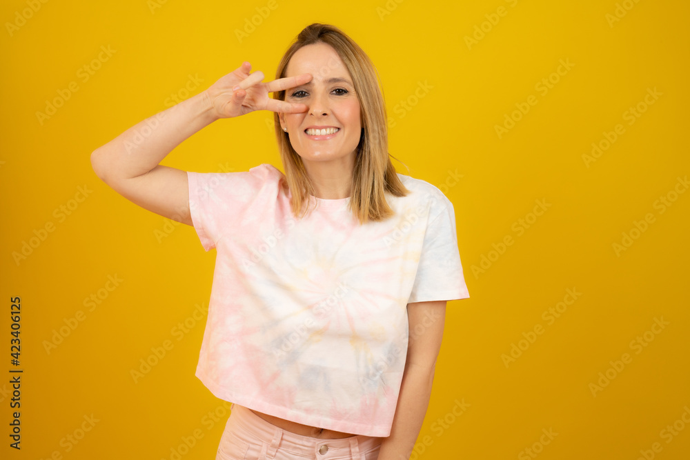Young woman isolated showing victory sign and smiling broadly. Young woman isolated showing victory sign and smiling broadly.