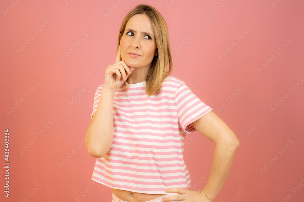 Portrait of a pensive casual woman looking away at copy space isolated over pink background Portrait of a pensive casual woman looking away at copy space isolated over pink background