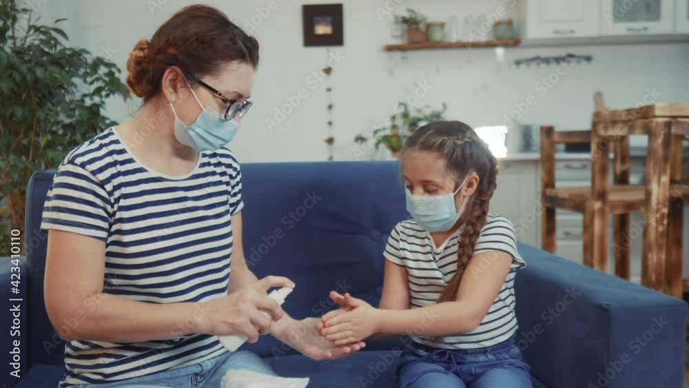 mom and daughter antiseptic sanitizer hand treatment protective medical mask. coronavirus concept. mom treats her hands with an antiseptic sanitizer to daughter. protection coronavirus social distance