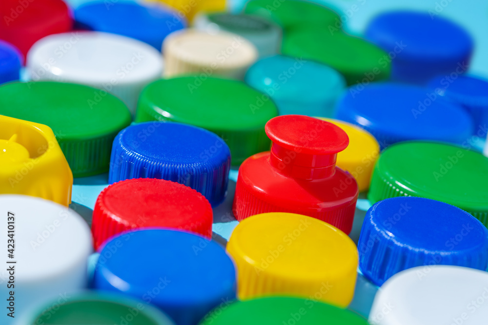 Colorful plastic bottle caps on a blue background, collecting plastic for recycling and reuse. Colorful plastic bottle caps on a blue background, collecting plastic for recycling and reuse.