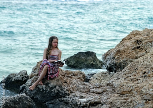 woman is sitting on rocks and reading a book  © Viktoriya