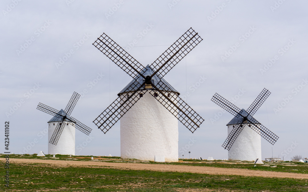 three whitewashed traditional Spanish windmills on the plains of La Mancha