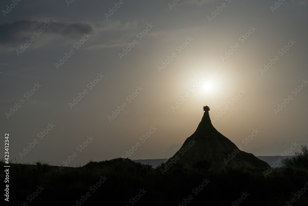 silhouette of rock pinnacle and mesa in a desert landscape with a setting sun