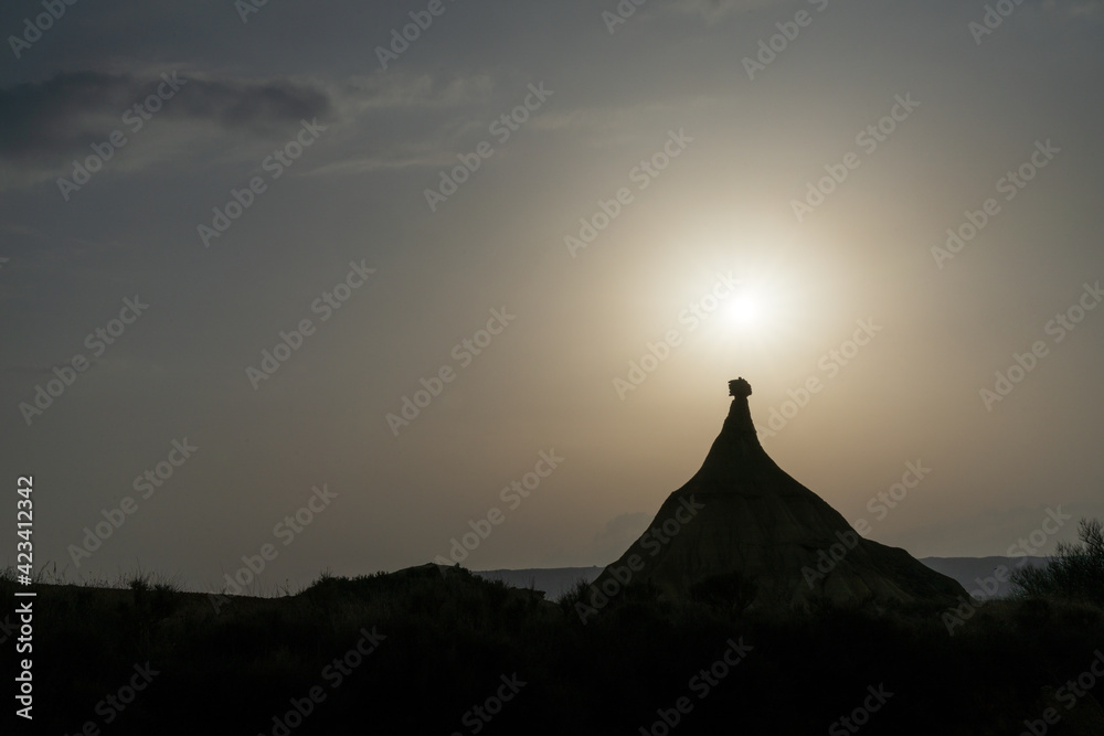 silhouette of rock pinnacle and mesa in a desert landscape with a setting sun silhouette of rock pinnacle and mesa in a desert landscape with a setting sun