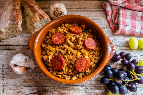 Migas Manchegas with chorizo in a clay pot, served with grapes, garlic and bread. It is a Spanish dish, traditional from Castilla la Mancha. photo