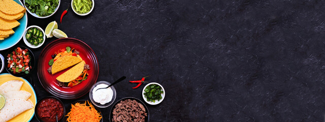 Taco bar corner border with an assortment of ingredients. Top view on a dark slate banner background. Mexican food buffet. Copy space.