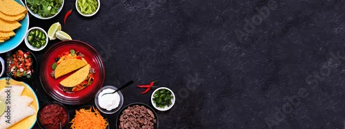 Obraz  z motywem Taco bar corner border with an assortment of ingredients. Top view on a dark slate banner background. Mexican food buffet. Copy space.