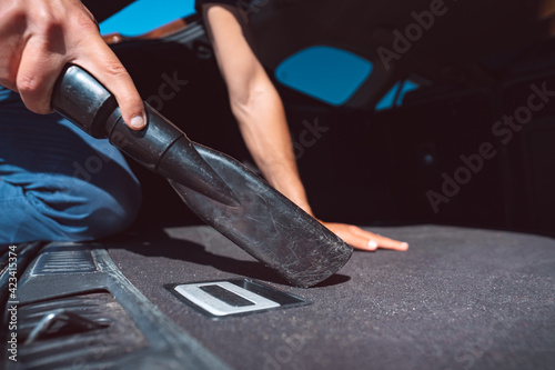 Man cleaning car inside with vacuum cleaner at self service car wash station.