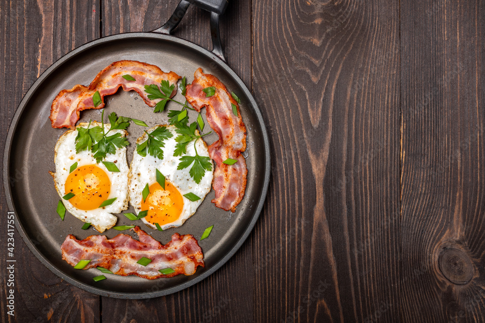 fried eggs with bacon and herbs on a frying pan top view fried eggs with bacon and herbs on a frying pan top view