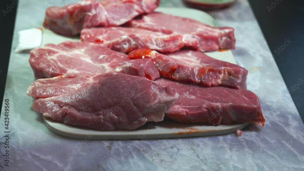 Close up view of sliced steak being salted and peppered before grilling. Close up view of sliced steak being salted and peppered before grilling.