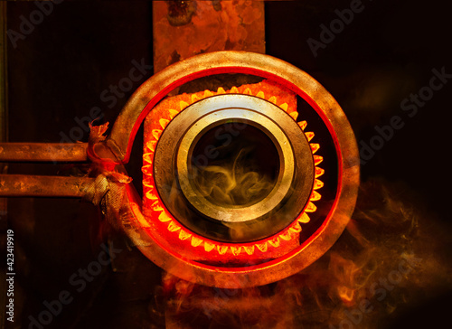 closeup calcining hot metal steel gear parts in a factory induction furnace with smoke