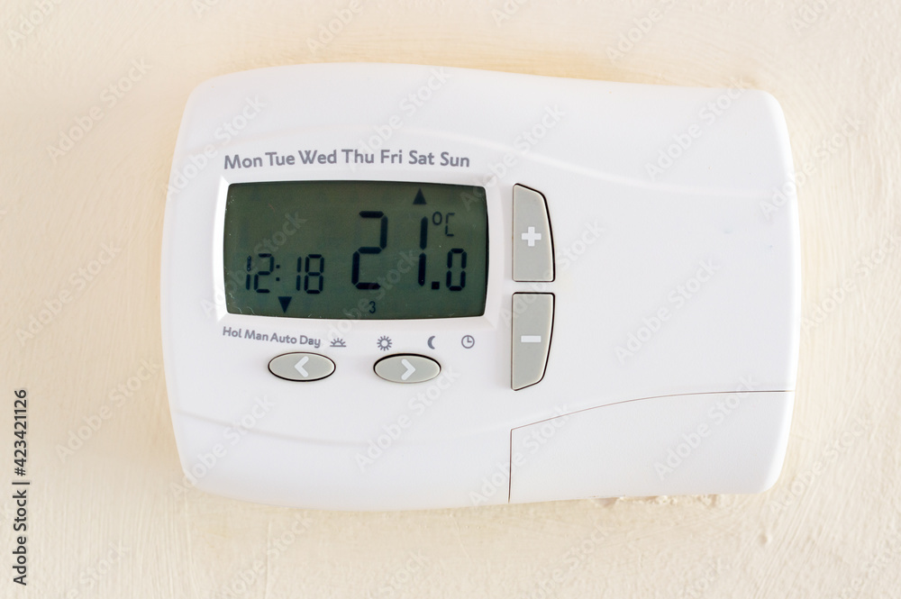 Digital thermostat mounted on wall displaying temperature in celcius Digital thermostat mounted on wall displaying temperature in celcius