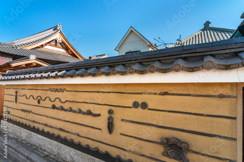 Wattle and daub wall of the Buddhist Youdenji Temple adorned with stacked roof tiles depicting motifs of waves and cicada in the traditional neighborhood of Yanaka. photo