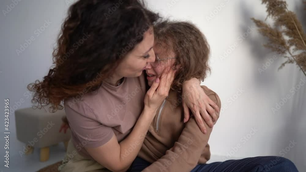 Mature mother calms her teenage daughter, wipes her tears and hugs her. Mother's day, motherhood concept Mature mother calms her teenage daughter, wipes her tears and hugs her. Mother's day, motherhood concept