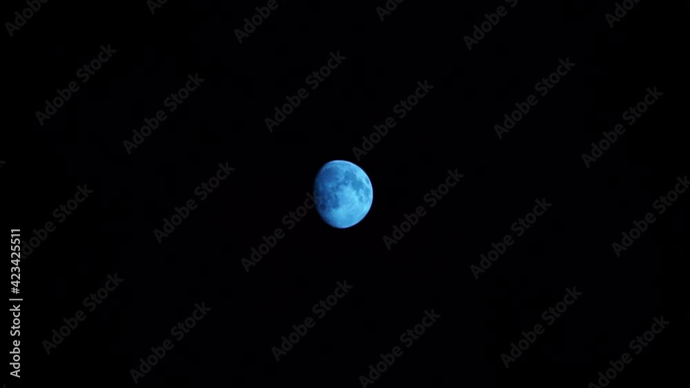 quelques petits nuages fins passent devant la lune bleue éclairée à 86 % dans un ciel complètement noir