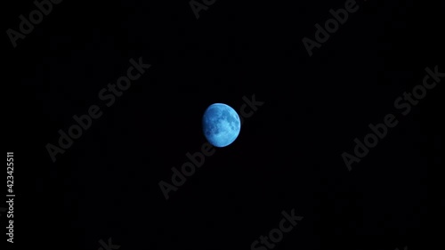 quelques petits nuages fins passent devant la lune bleue éclairée à 86 % dans un ciel complètement noir