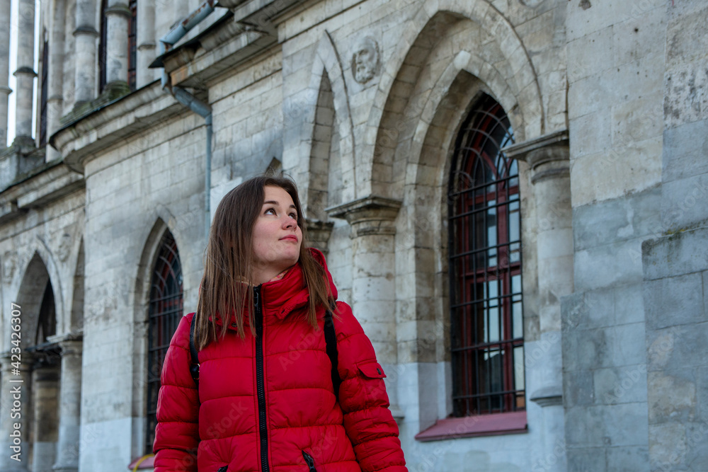 Girl in red near the wall of an old building