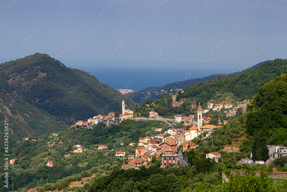 Wonderful view of the Italian village in the mountains. Against the background of the sea in the haze.