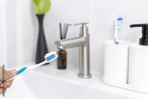 Man holds toothbrush with toothpaste in the bathroom