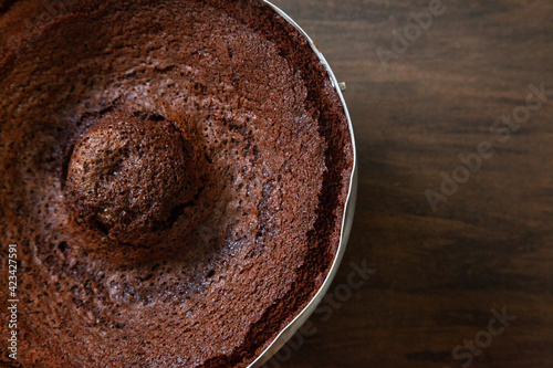 Chocolate cake in the form, withered, sank. Wooden background, view from above. Space for design.
