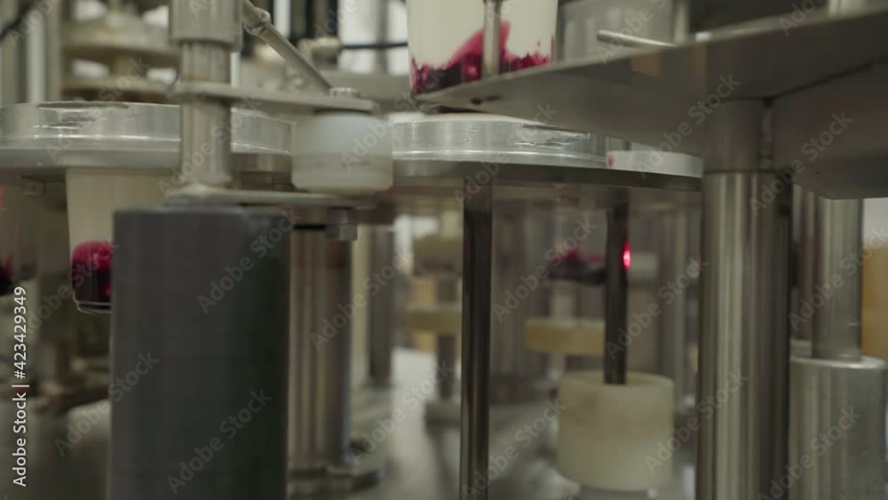 Dairy factory. A lot of Yogurt containers are getting capped and are ...