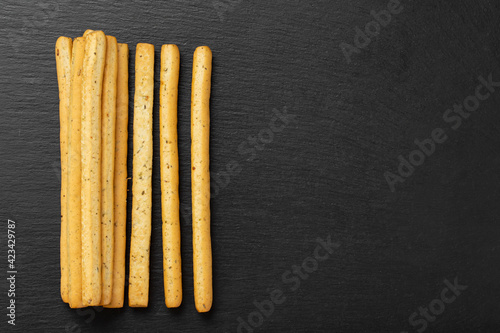 Homemade Italian Grissini Breadsticks on a black background. Traditional italian snack with herbs.  Space for text.